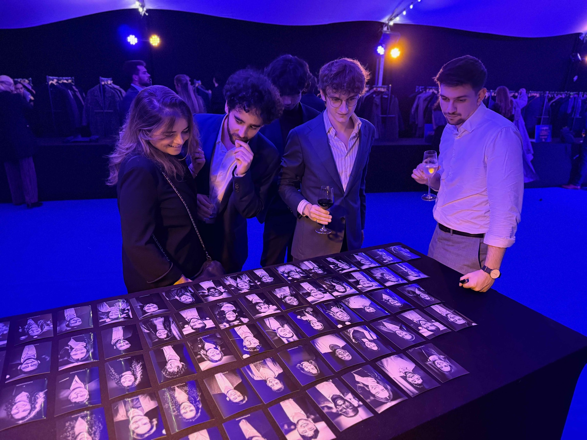 Des invités découvrent la mosaïque de portraits posée sur une grande table, lors d'une soirée de gala