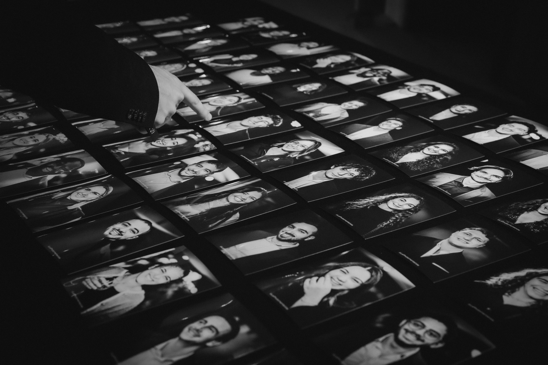 Une main pointe un portrait du doigt sur la mosaïque de tirages noir et blanc